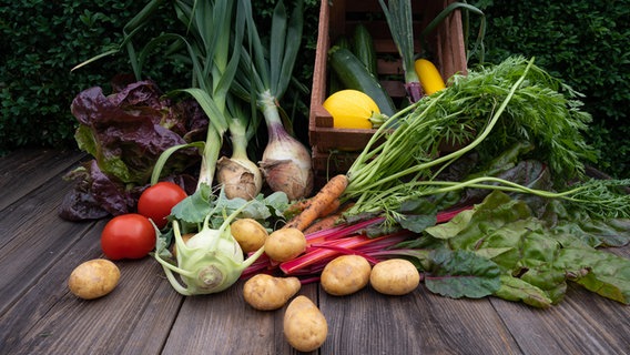 Verschiedene Gemüsesorten wie Kartoffeln und Salat liegen drapiert auf einem Holzboden. © picture alliance/Countrypixel Foto: FRP