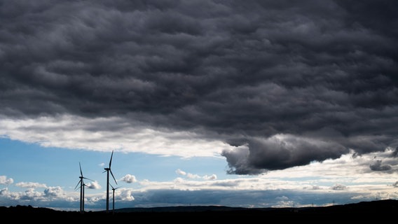 Ciemne chmury burzowe mijają turbiny wiatrowe.  © Image Alliance/dpa Zdjęcie: Julian Stratensult