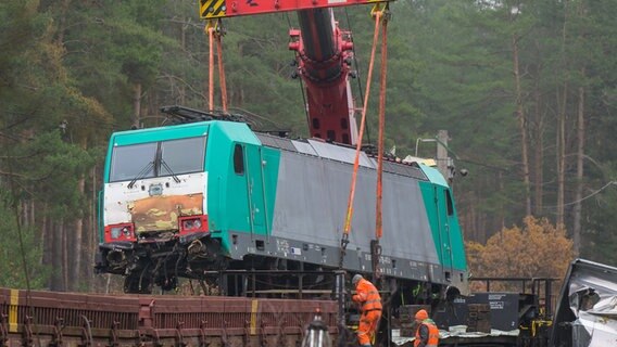 Eine verunfallte Lok wird mit einem Kran auf einen Waggon gehoben. © dpa-Bildfunk Foto: Philipp Schulze/dpa