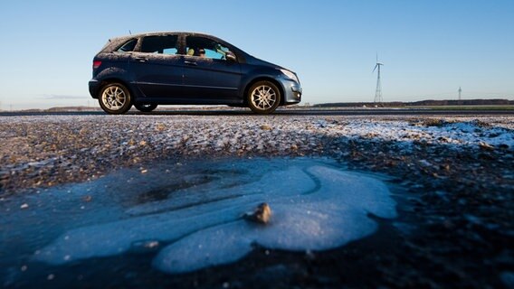 Eisbildung auf einer STraße. Dahinter ein Auto. © picture alliance/dpa/Julian Stratenschulte Foto: Julian Stratenschulte