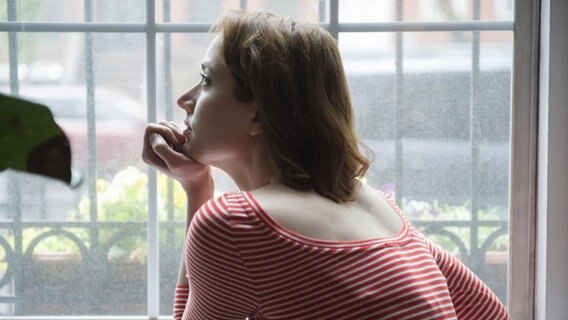 Eine Frau blickt auf ihre Hand gestützt aus dem Fenster. © picture alliance/Bildagentur-online Foto: Blend Images/JGI