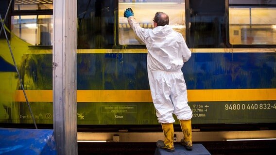 Ein Mann entfernt Graffiti von einem Zug der Nord-West-Bahn. © dpa-Bildfunk Foto: Sina Schuldt