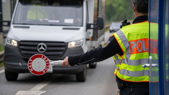 Ein Polizist fordert einen Transporter mit Kelle zum Halten auf. © dpa Bildfunk Foto: Harald Tittel/dpa