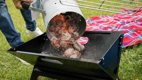 Glut wird aus einer Tonne in einen Grill geschüttet. © picture alliance/dpa-tmn/Christin Klose Foto: Christin Klose