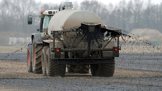 Ein Traktor zieht einen Güllewagen über ein Feld und versprüht Gülle. © dpa-Bildfunk Foto: Ingo Wagner