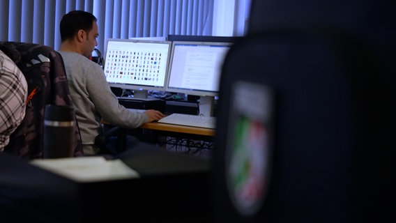 Ein Polizist sitzt an einem Rechner. © NDR 