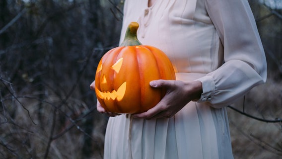Eine Person hält einen Halloween-Kürbis in der Hand. © picture alliance / Shotshop | Addictive Stock 