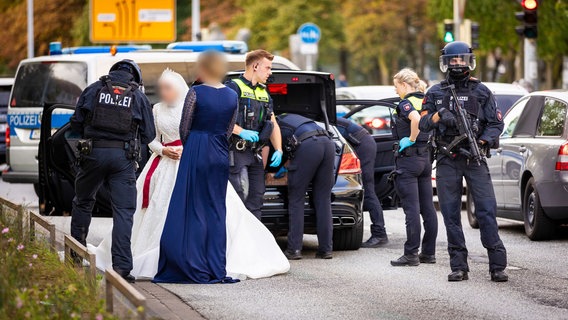 Polizisten kontrollieren Teilnehmer eines Hochzeitskorsos und ihre Fahrzeuge. © Moritz Frankenberg/dpa Foto: Moritz Frankenberg