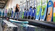 Eine Frau steht während der Freizeitmesse abf auf einem Surfboard. © dpa-Bildfunk Foto: Holger Hollemann