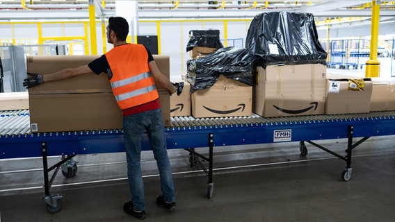 Ein Amazon-Mitarbeiter steht an einem Fließband. © dpa-Bildfunk Foto: Peter Steffen