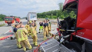 Einsatzkräfte der Feuerwehr Hannover stehen neben einem verunfallten Lkw auf der Autobahn A7 im Autobahnkreuz Hannover-Ost. © dpa-Bildfunk Foto: Julian Stratenschulte