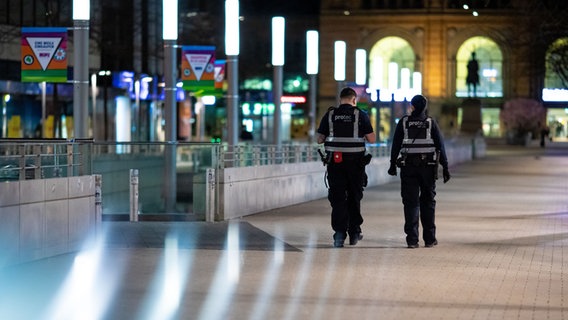 Zwei Mitarbeitende eines Sicherheitsdienstes gehen am Abend des 1. April 2021 durch Hannovers Innenstadt. © Picture Alliance Foto: Moritz Frankenberg