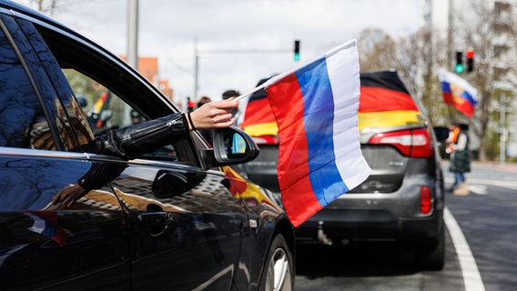 Eine Frau hält eine russische Flagge aus dem Beifahrer-Fenster eines Autos. © Picture Alliance Foto: Michael Matthey