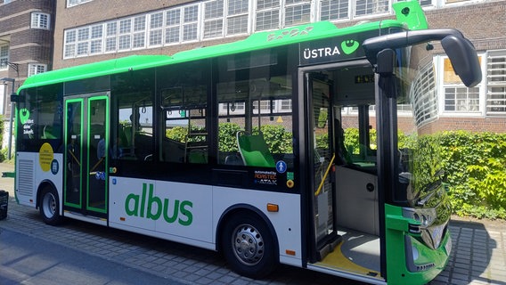 Ein Elektrobus mit der Aufschrift albus steht mit geöffneter Vordertür vor einem Gebäude. © NDR Foto: Kristin Häfemeier