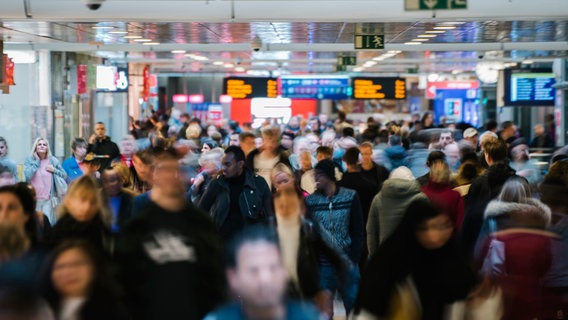 Numerous people can be seen in Hanover Central Station, with scoreboards in the background.  © NDR Photo: Julius Matuschik