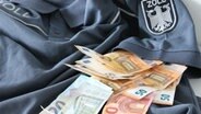 Mehrere Geldscheine liegen auf einem Diensthemd vom Zoll. © Polizei Hannover 
