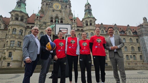 Die Basketballerinnen Karolin Tzokov (Dritte von links), Marie Reichert, Victoria Poros und Meret Kleine-Beek stehen mit Oberbürgermeister Belit Onay (Zweiter von links), Regionspräsident Steffen Krach (rechts) und Jürgen Wache (links) von der Volksbank vor dem Neuen Rathaus in Hannover. © NDR / Bernd Reiser Foto: Bernd Reiser