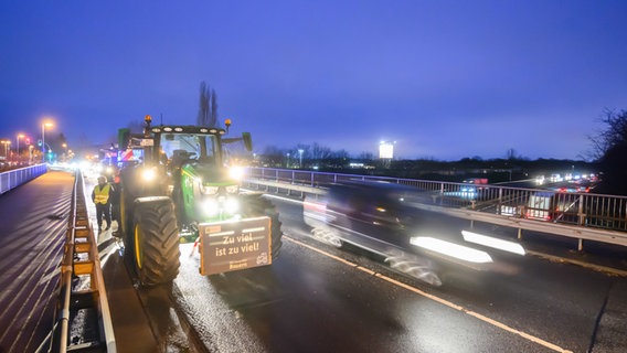 Bauern stehen mit Traktoren auf einer Brücke über der Autobahn A2 bei Garbsen in der Region Hannover. © dpa-Bildfunk Foto: Julian Stratenschulte