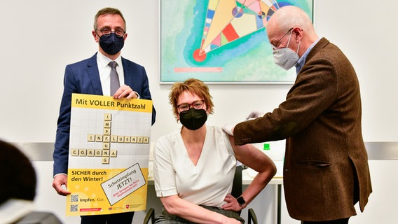 Gesundheitsministerin Daniela Behrens wird geimpft von Dr. Jörg Berling (KVN). Links im Bild Dr. Fabian Feil, Präsident des NLGA. © Niedersächsisches Landesgesundheitsamt 