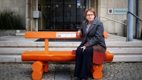 Niedersachsens Sozialministerin Daniela Behrens (SPD) sitzt auf einer orangefarbenen Bank, auf der ein Schild mit dem Text "Kein Platz für Gewalt an Frauen" montiert ist. © Niedersächsisches Ministerium für Soziales, Arbeit, Gesundheit und Gleichstellung 