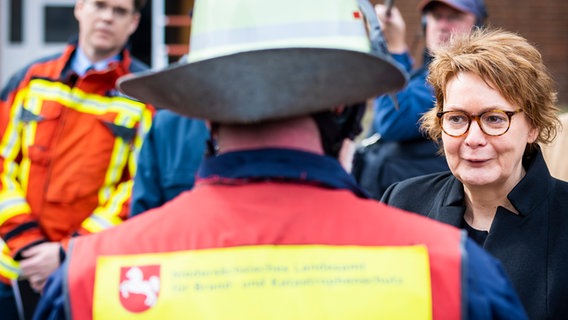 Minister spraw wewnętrznych Daniela Behrens (SPD) rozmawia ze strażakiem podczas jej inauguracyjnej wizyty w NLBK.  © Image Alliance/dpa |  Moritz Frankenberg Zdjęcie: Moritz Frankenberg