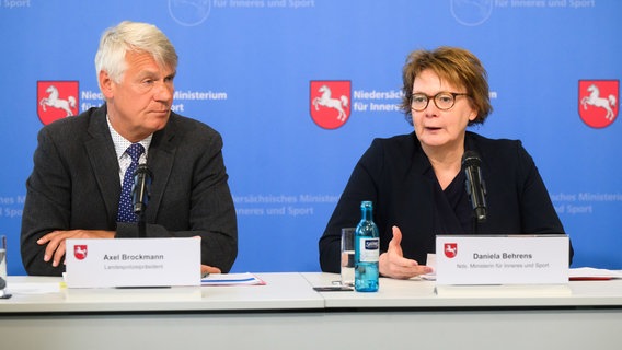 Landespolizeipräsident Axel Brockmann (l) und Innenministerin Daniela Behrens (SPD) informieren bei einer Pressekonferenz im Innenministerium über politisch motivierte Kriminalität in Niedersachsen 2024. Sie sitzen auf Stühlen, vor ihnen stehen Mikrofone. © dpa-Bildfunk Foto: Julian Stratenschulte