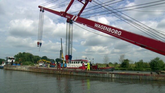 Ein Kran befindet sich zur Bergung eines havarierten Binnenschiffes an der Weser. © NDR 