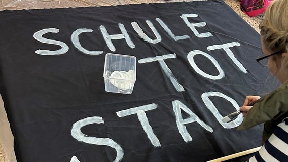 Eine Frau schreibt auf schwarzen Stoff "Schule tot Stadt tot" © Michaela Meier 