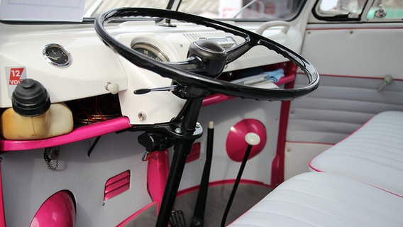 Der Innenraum eines VW-Busses leuchtet in den Farben Rosa und Weiß. © NDR Foto: Eric Klitzke