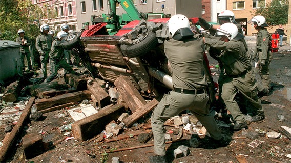 Mehrere Polizisten versuchen während der Chaostage 1995 einen Pkw wieder auf die Räder zu stellen. © dpa-Bildfunk Foto: Holger Hollemann