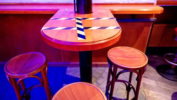 Barhocker stehen an einem mit Klebeband abgesperrten Tisch in einem Club in Hannover. © dpa Foto: Hauke-Christian Dittrich