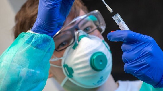 Ein Mitarbeiter steckt nach einem Corona-Test ein Abstrichstäbchen in ein Plastikgefäß. © dpa-Bildfunk Foto: Jens Büttner