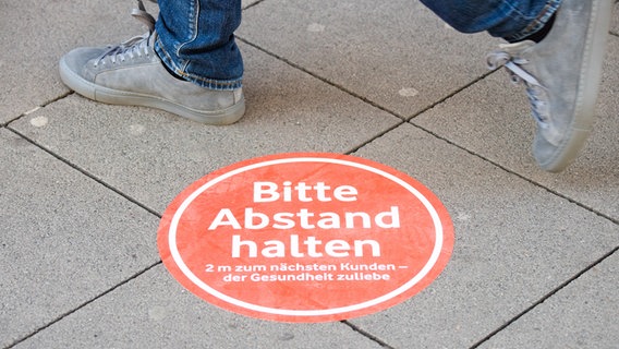 Ein Aufkleber auf dem Boden fordert zum Abstand halten auf. © dpa-Bildfunk Foto: Julian Stratenschulte