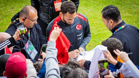 Hakan Çalhanolu (M) gibt beim öffentlichen Training der türkischen Nationalmannschaft vor der EM in Barsinghausen Autogramme. © Moritz Frankenberg/dpa Foto: Moritz Frankenberg/dpa