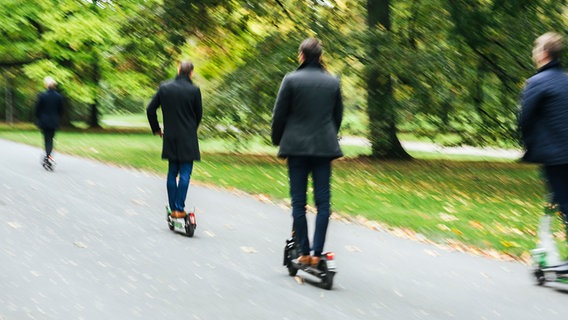 In Hannover sind mehrere Personen zu sehen, die mit E-Scootern durch einen Park fahren. © NDR Foto: Julius Matuschik