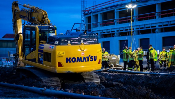 Einsatzkräfte der Feuerwehr errichten einen Lichtmast auf einer Baustelle in der Region Hannover, auf der eine Fliegerbombe aus dem Zweiten Weltkrieg gefunden wurde. © Moritz Frankenberg/dpa Foto: Moritz Frankenberg/dpa