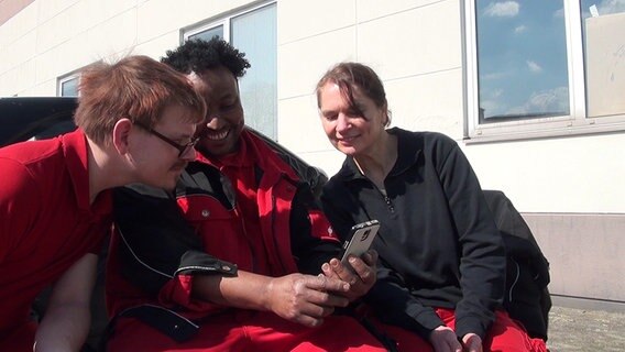 Drei Menschen schauen auf ein Smartphone. © NDR Foto: NDR