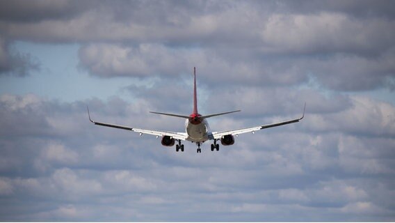 Ein Flugzeug fliegt vom Betrachter weg durch einen bewölkten Himmel. © picture alliance/dpa Foto: Julian Stratenschulte
