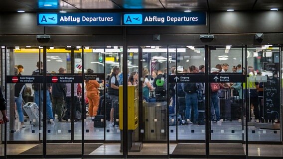Menschen warten in einer Schlange am Flughafen in Langenhagen. © Lino Mirgeler/dpa Foto: Lino Mirgeler