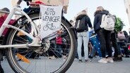 An einem Fahrrad hängt ein Schild mit der Aufschrift "Ein Auto weniger". © dpa - Bildfunk Foto: Julian Stratenschulte