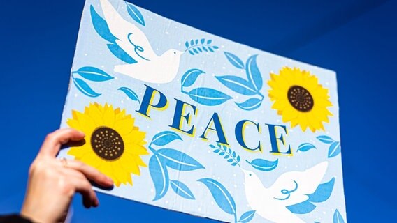 Der Schriftzug "PEACE" ist auf dem Plakat einer Demonstrantin auf einer Demonstration gegen den Angriff Russlands auf die Ukraine zu lesen. © picture alliance/dpa Foto: picture alliance/dpa | Moritz Frankenberg