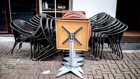 Zusammengestellte Stühle und Tische einer Gastronomie stehen in einer Straße. © picture alliance/dpa | Hauke-Christian Dittrich Foto: Hauke-Christian Dittrich