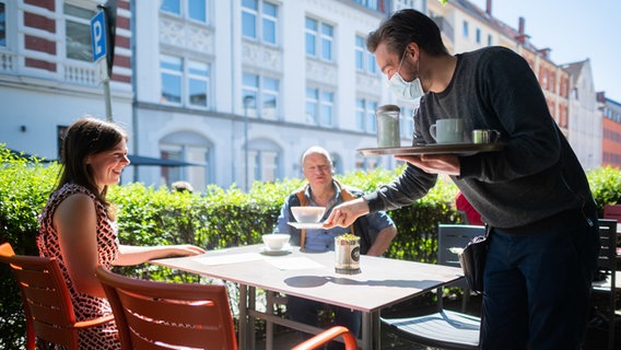 Hannover: Ein Kellner serviert auf der Außenterrasse eines Cafés an der Lister Meile Kaffee für zwei Gäste. © dpa-Bildfunk Foto: Julian Stratenschulte