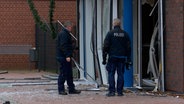Polizisten stehen vor dem zerstörten Eingangsbereich einer Bankfiliale in Winsen/Aller, nachdem Unbekannte einen Geldautomaten gesprengt haben. © HannoverReporter 