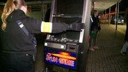 Eine Polizistin hält einen Spielautomaten fest. Er wird in Hannover beschlagnahmt. © TNN 