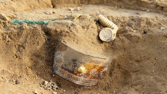 Ein goldener Armreif des Goldschatzes von Gessel liegt im Sand (Archivbild). © dpa - Bildfunk Foto: Bernd Rasink / Niedersächsischen Landesamt für Denkmalpflege