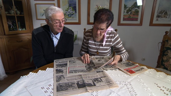 Siegfried und Gisela Schilberg sitzen an einem Tisch, auf dem Zeitungsberichte über die Geiselnahme in Groß Düngen liegen. © NDR 