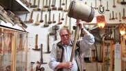 Georg Peters hält einen großen Holzhammer über seinen Kopf. © NDR Foto: Eric Klitzke
