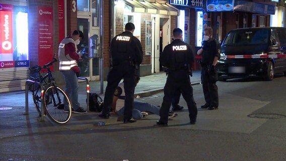 Polizisten stehen um einen Mann auf dem Boden mit den Händen hinter den Rücken gebunden. © TeleNewsNetwork 