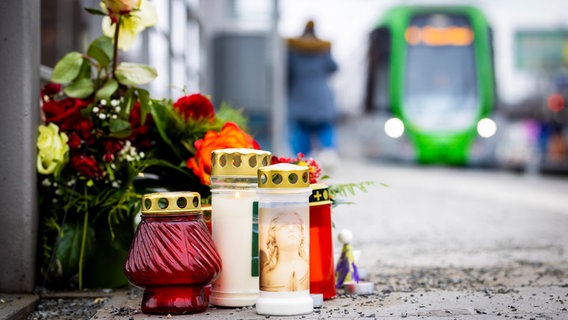 Blumen und Kerzen liegen an einem Bahnsteig der Stadtbahnhaltestelle «Fiedelerstraße» im Stadtteil Döhren. © picture alliance/dpa Foto: Moritz Frankenberg